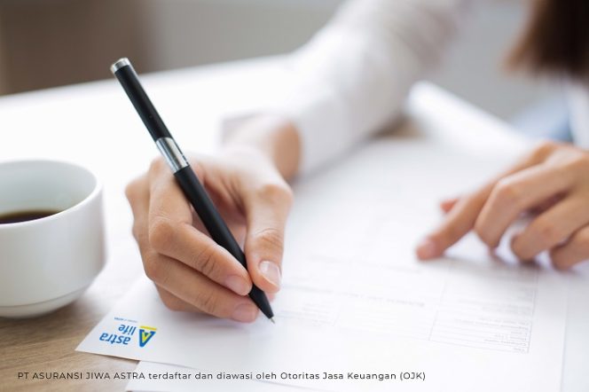 
					Cropped view of woman holding pen and filling out application form at table with focus on hand with pen